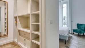 Une chambre à coucher avec un lit, un fauteuil de couleur turquoise et un plancher en bois.