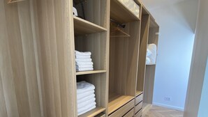 A walk-in closet with wooden shelving, drawers, and hanging space. - Appart Privé Deluxe Strasbourg City (Strasbourg)