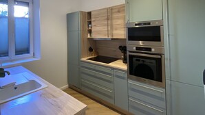 A modern kitchen with light blue cabinets, a wooden countertop, and built-in appliances including a stove and oven. - Appart Privé Deluxe Strasbourg City (Strasbourg)