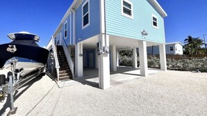 Ein zweistöckiges Haus mit überdachter Veranda und einem Boot im Vorgewässer.