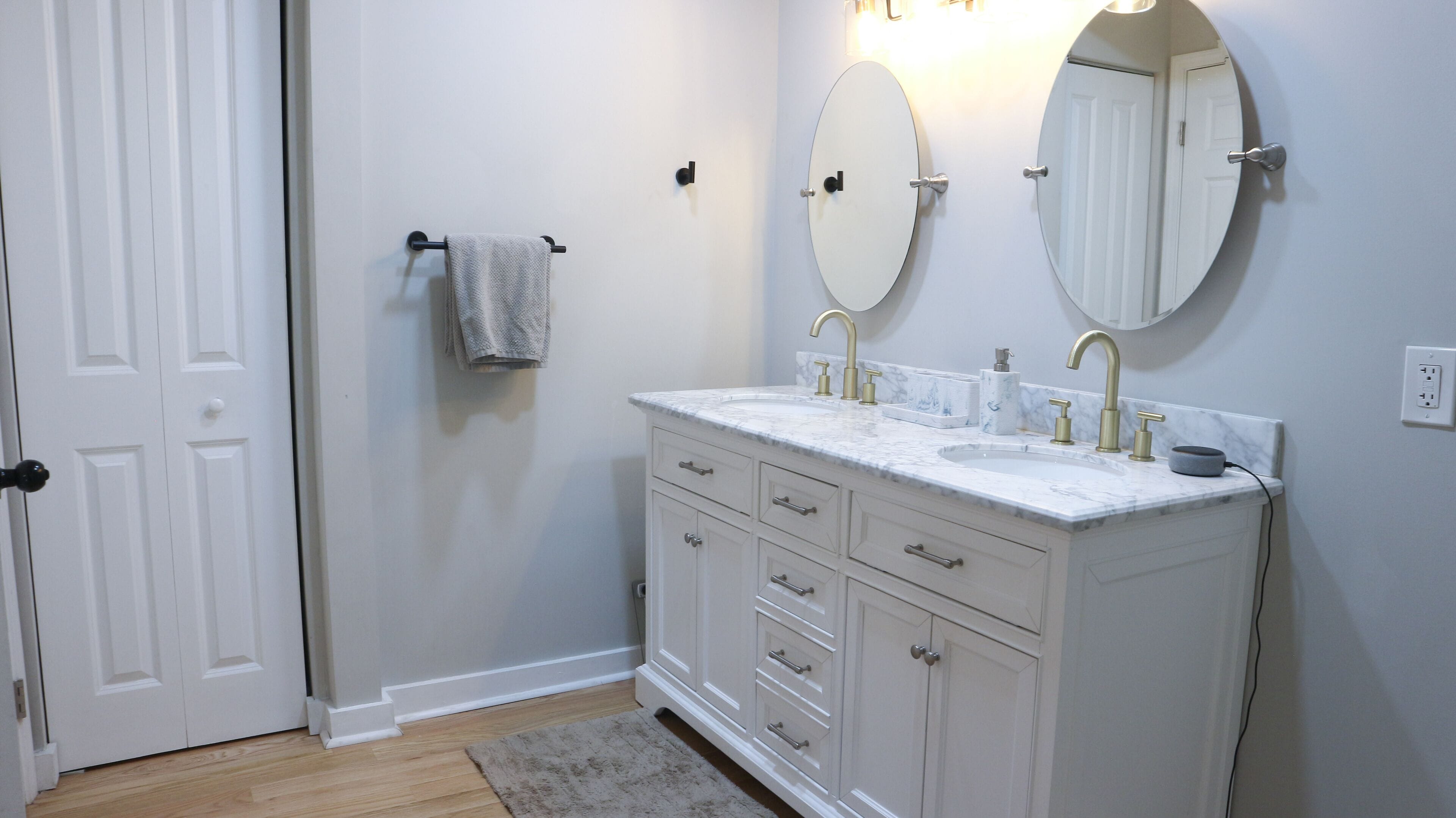 A bathroom with white cabinetry, a sink with gold fixtures, and two wall-mounted mirrors.