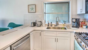 Een moderne keuken met witte kasten, een roestvrijstalen spoelbak en een gasfornuis.