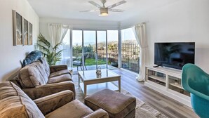 Een moderne woonkamer met een bank, voetenbankje en een televisie op een meubel.