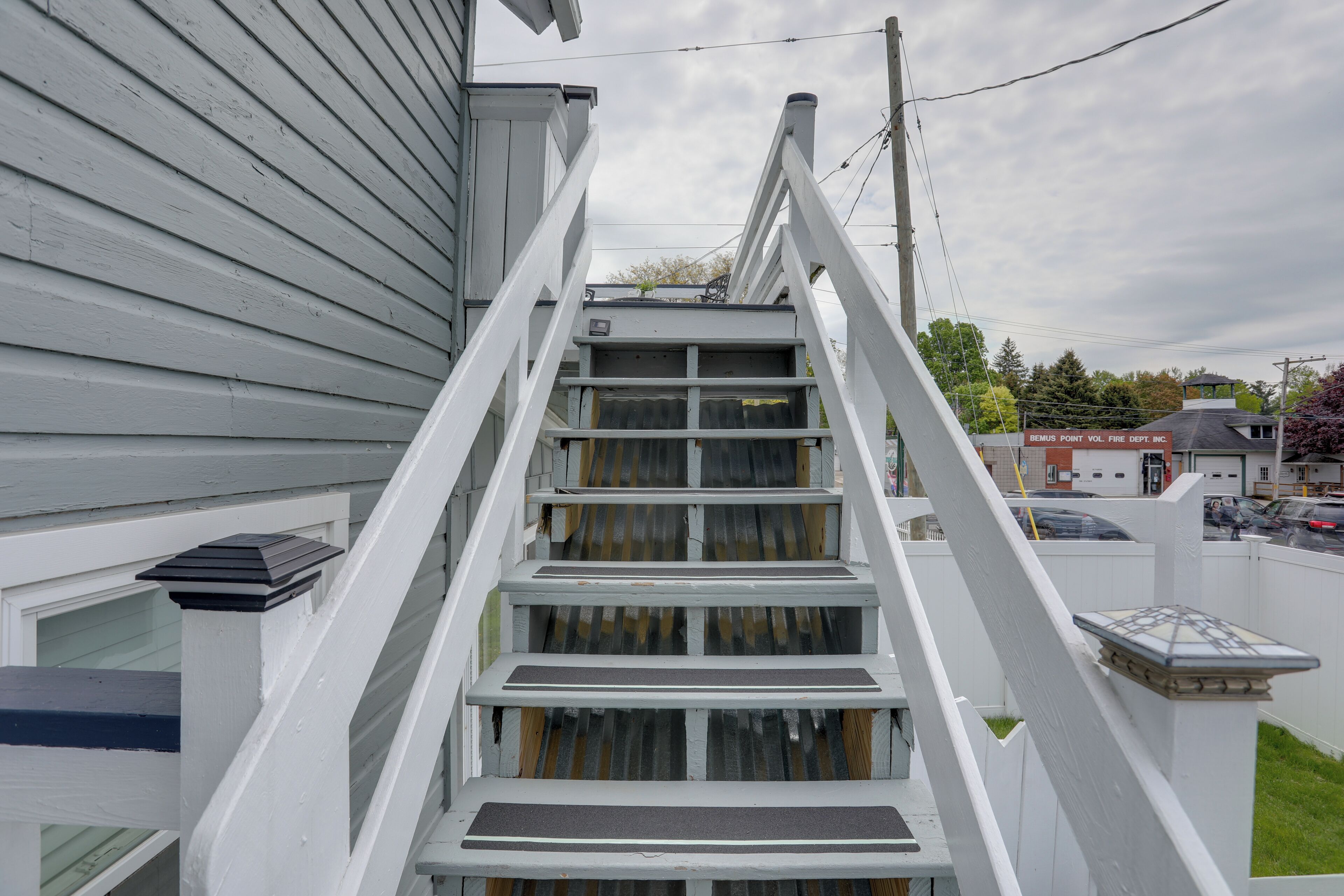 A white wooden staircase leading to a house with a window and a door.
