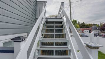 A white wooden staircase leading to a house with a window and a door.