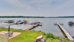 A lakeside dock with boats, a covered seating area, and a grassy deck.