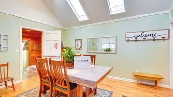 A dining area with a wooden table and chairs, a 'welcome' sign, a mirror, and a bench.