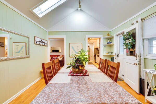 A dining area with a high ceiling, a skylight, and a view into another room.