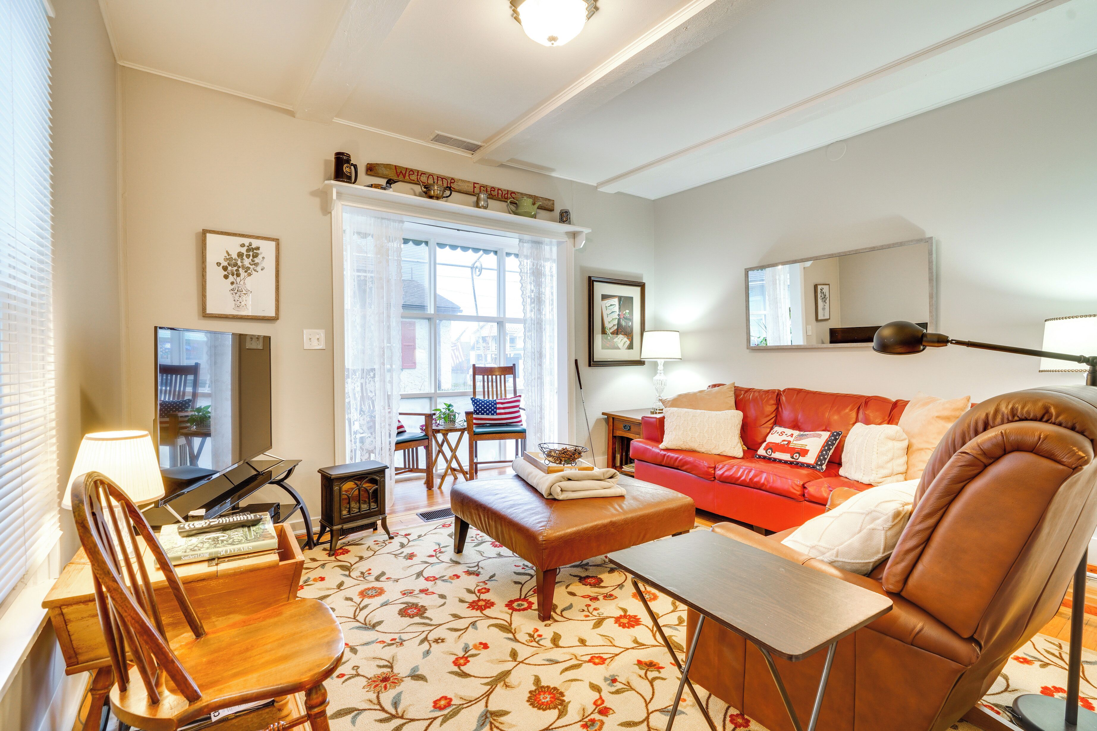 A living room with a red sofa, a wooden coffee table, a brown leather armchair, a wooden side table, a lamp, and a framed picture on the wall.