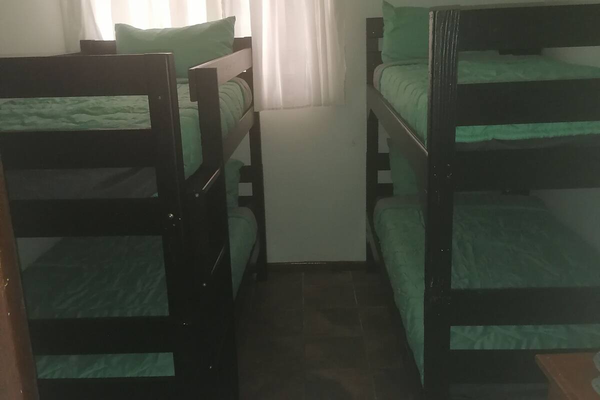 Ein Zimmer mit zwei Etagenbetten, einem fenster mit Vorhängen und einem Fliesenboden.