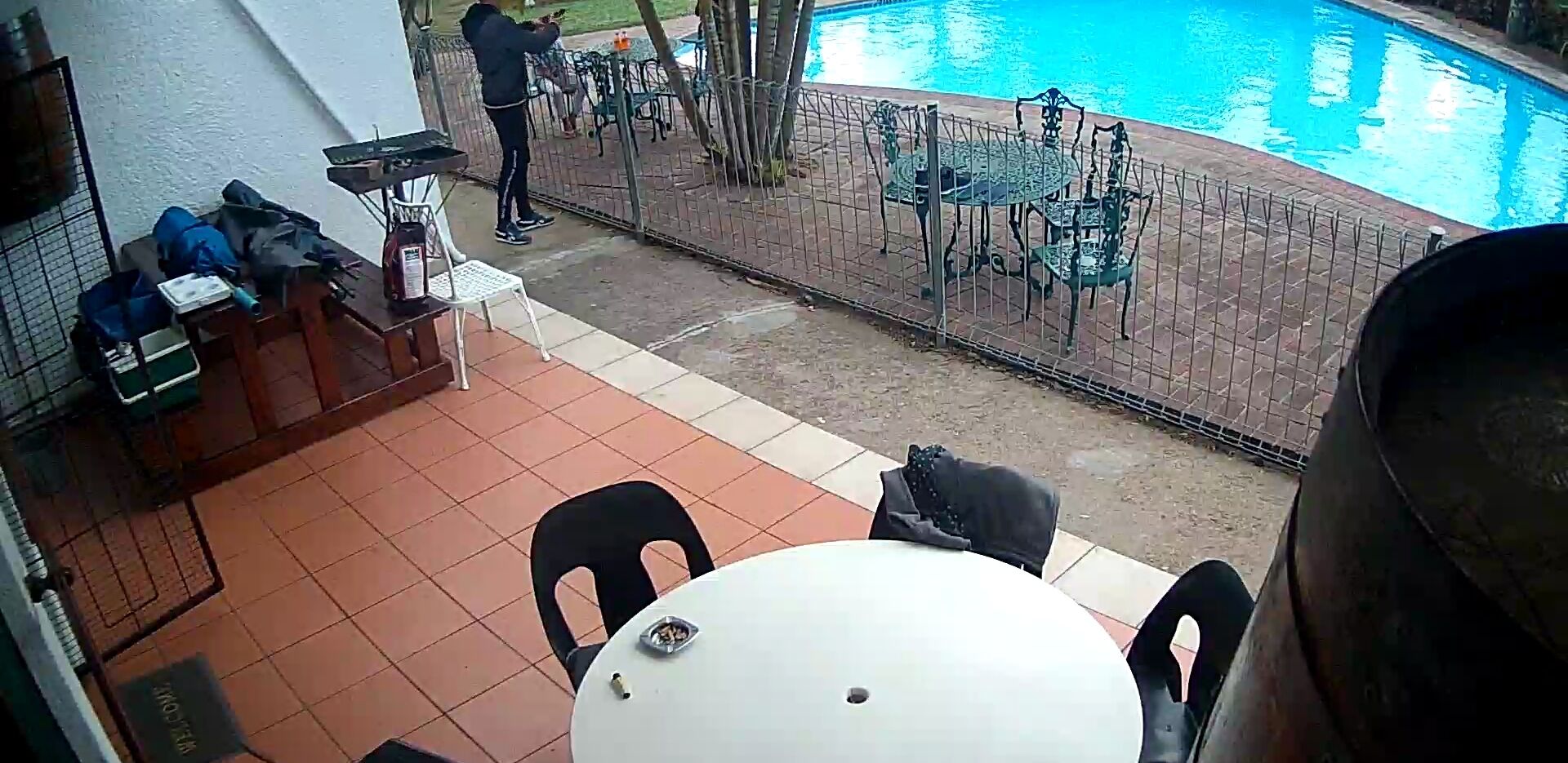 A patio area with a pool, outdoor seating, and a grill.