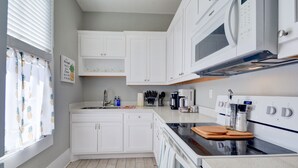 A modern kitchen with white cabinets, a black countertop, and a built-in oven. - Beauty on Ball - Main 2 - King Bed, Near restaurants and beach!! (Galveston)