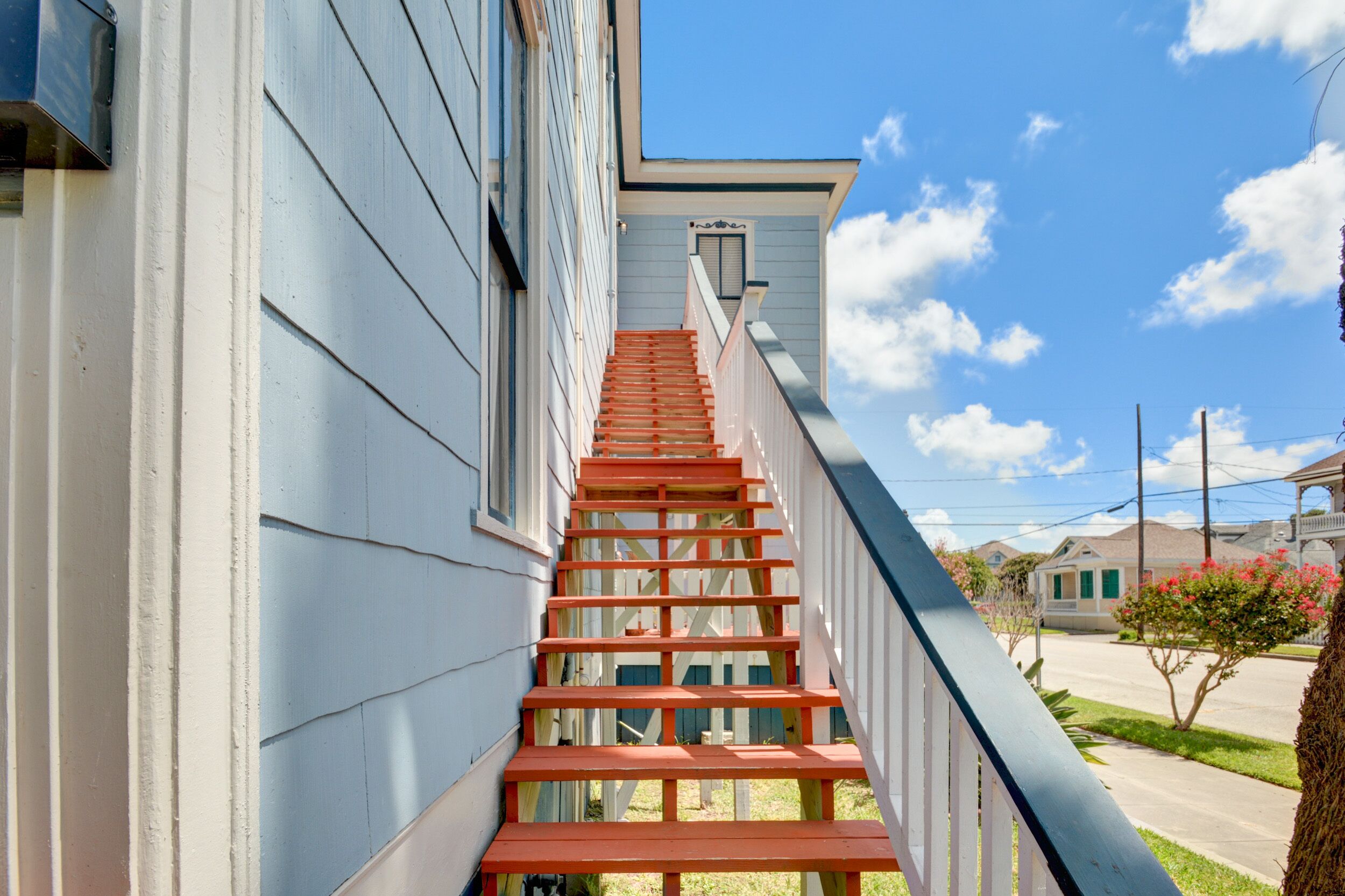 Un escalier menant à une maison, avec un ciel bleu clair en arrière-plan.