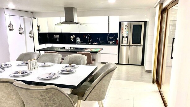 A modern kitchen with a central island, stainless steel appliances, and a dining area with a table set for four. - CASA SUYTE LEGUIZAMON (Envigado)