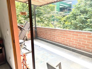 Un balcone con un muro in mattoni, una sedia in metallo e un tavolo.