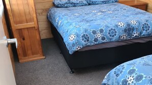 A room with two beds, a wooden wardrobe, and a carpeted floor.