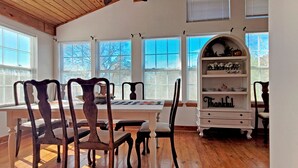 A dining area with wooden chairs, a white table, and a 'Thankful' decorative shelf.