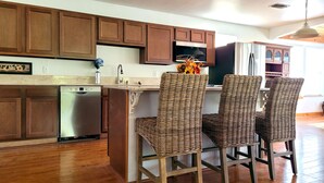 A kitchen with wooden cabinets, a dishwasher, a microwave, and two wicker chairs.