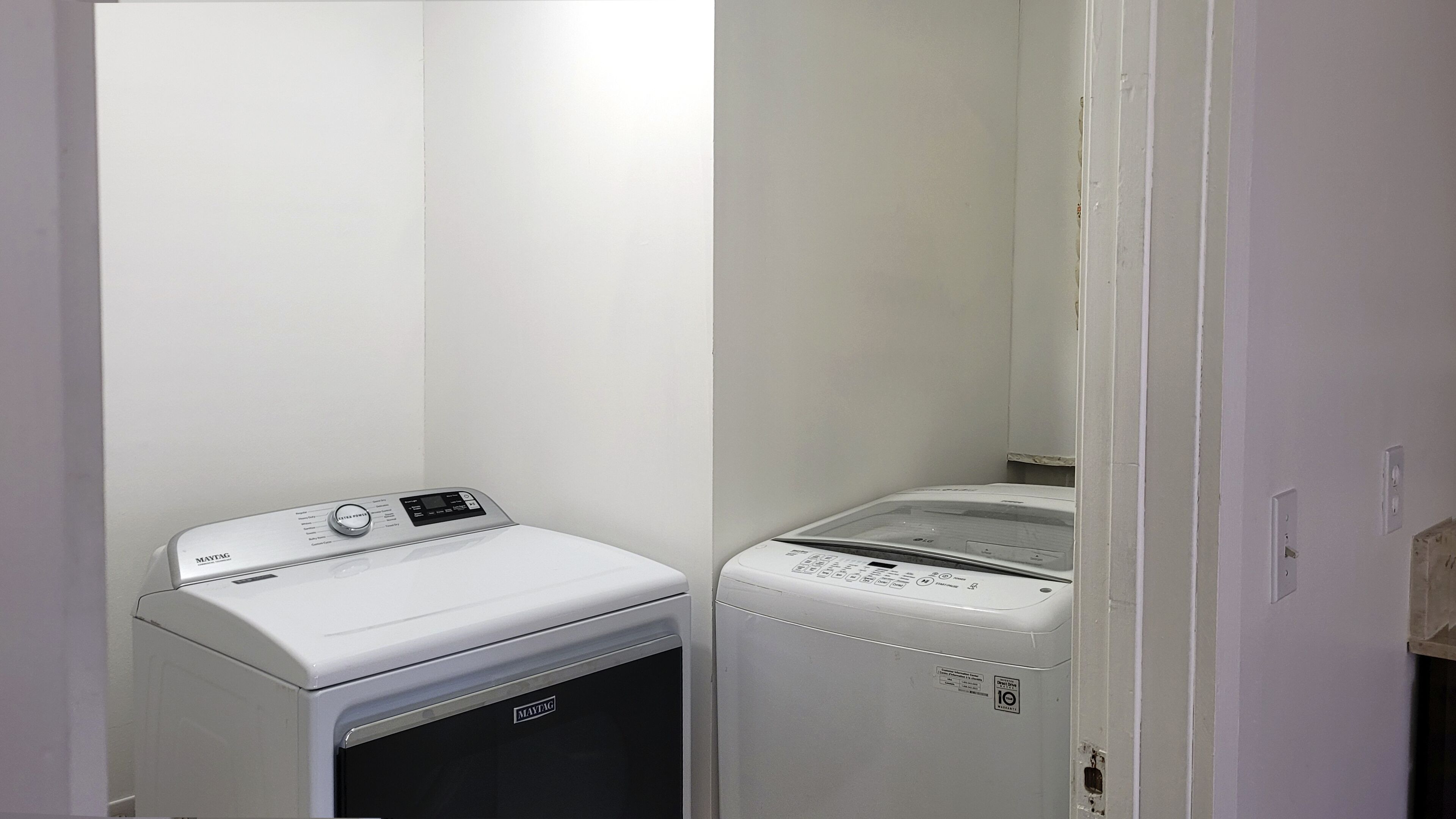Une buanderie équipée de deux machines à laver et de deux sèche-linge Maytag blancs.