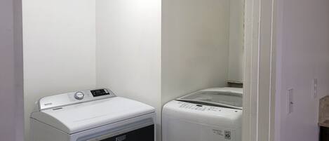 Une buanderie équipée de deux machines à laver et de deux sèche-linge Maytag blancs.
