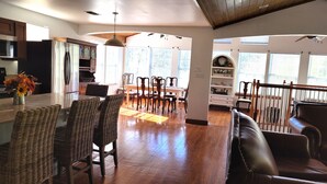 A spacious kitchen with modern appliances, a dining area with wicker chairs, and a cozy seating area with a leather couch.