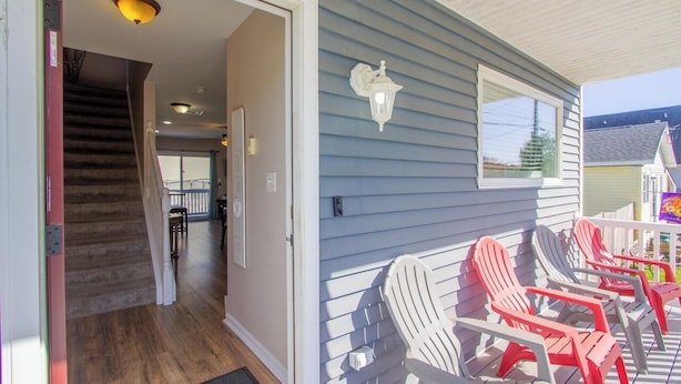 A wooden staircase leading to an interior room, a porch with Adirondack chairs, and a white exterior wall. - Beach Retreat I HotTub I FirePit I Near Cape May I 7 Beach Passes I 4 Bikes (Lower Township)