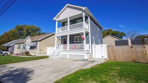 A two-story house with a front porch and a flag. - Beach Retreat I HotTub I FirePit I Near Cape May I 7 Beach Passes I 4 Bikes (Lower Township)