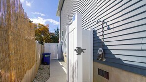 A narrow outdoor pathway leading to a house with a white exterior and a metal gate. - Beach Retreat I HotTub I FirePit I Near Cape May I 7 Beach Passes I 4 Bikes (Lower Township)