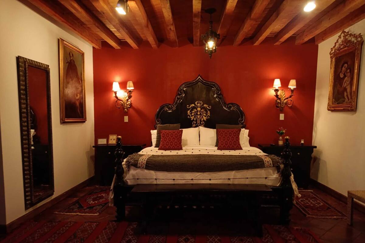 Une chambre à coucher de style traditionnel, avec une tête de lit en bois, deux lampes de chevet et des tapis à motifs.