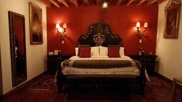 A traditional bedroom with a wooden headboard, two bedside lamps, and patterned rugs.