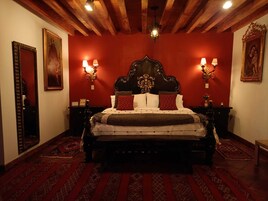 A traditional bedroom with a wooden headboard, two bedside lamps, and patterned rugs.