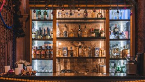 A bar with shelves of liquor bottles, a coffee machine, and a decorative Christmas tree.