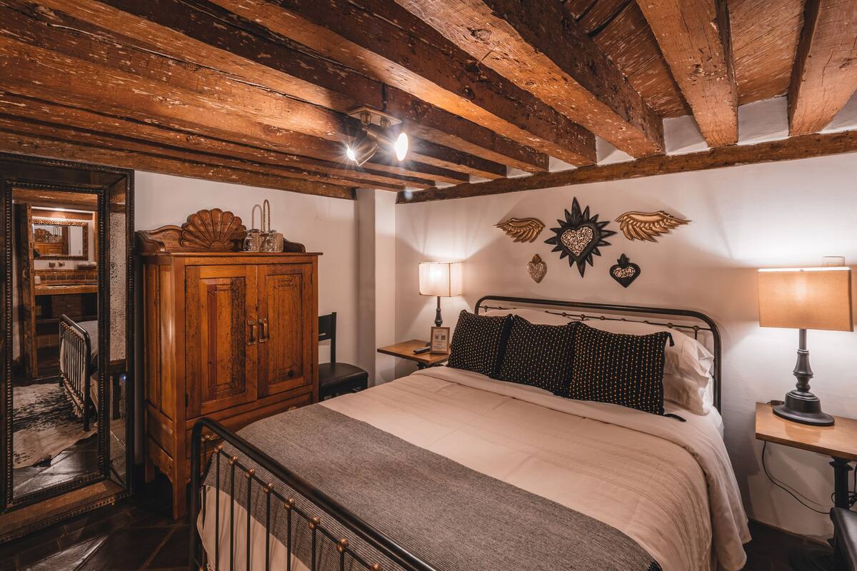 Une chambre à coucher avec un lit en bois, une table de chevet avec une lampe, une armoire en bois et un miroir.