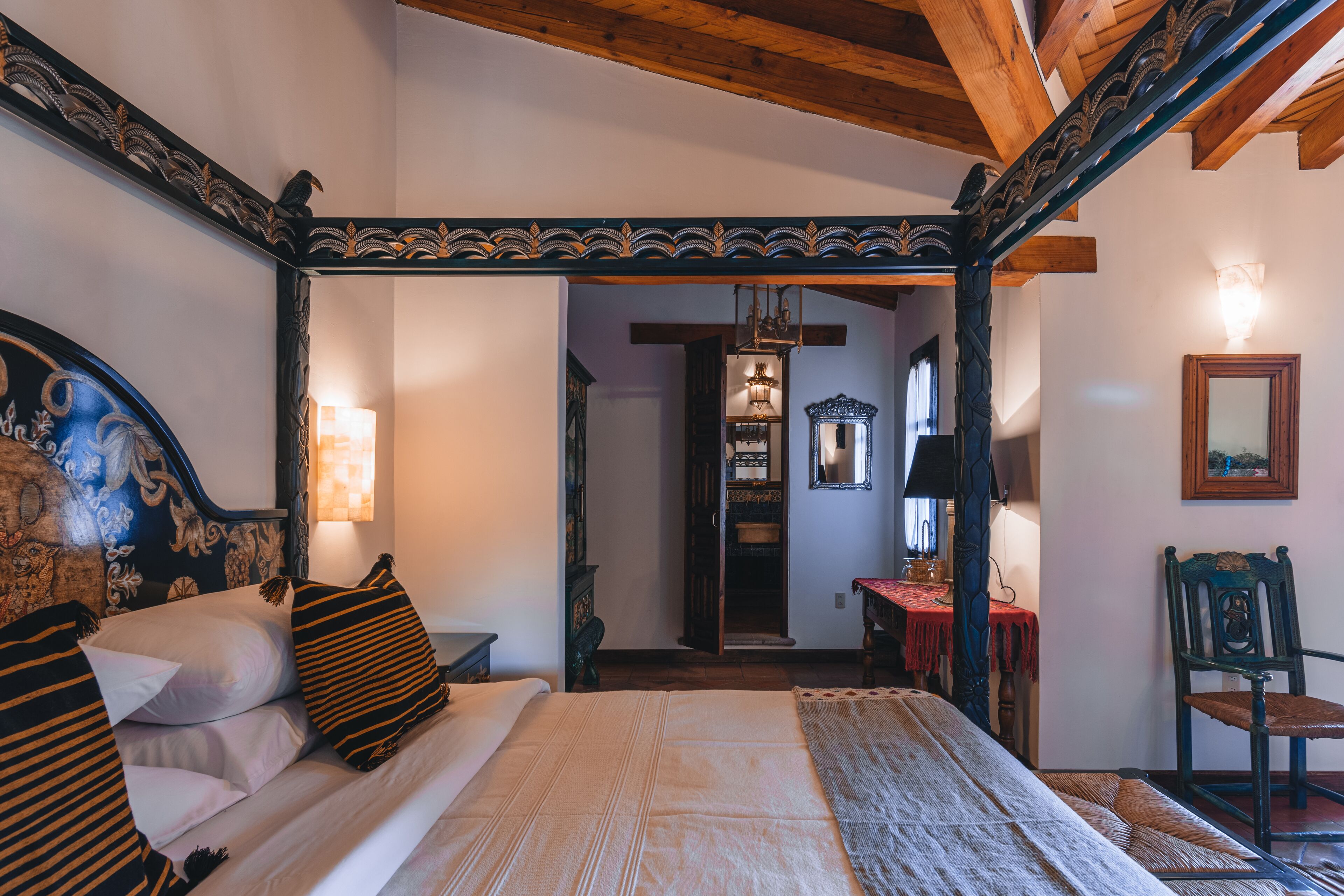 Une chambre traditionnelle avec un lit à baldaquin, un plafond en bois et un miroir au mur.
