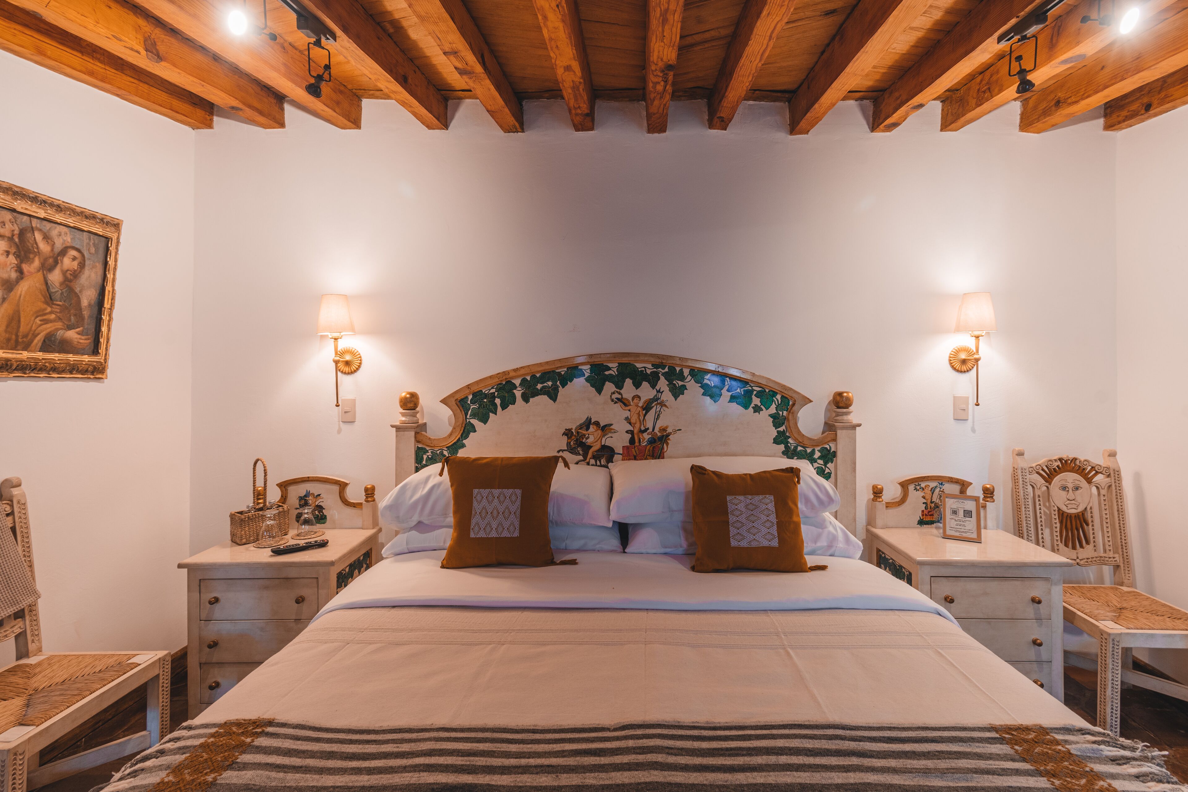 A neatly arranged bedroom with a large bed, two bedside tables, a nightstand, and a chair.