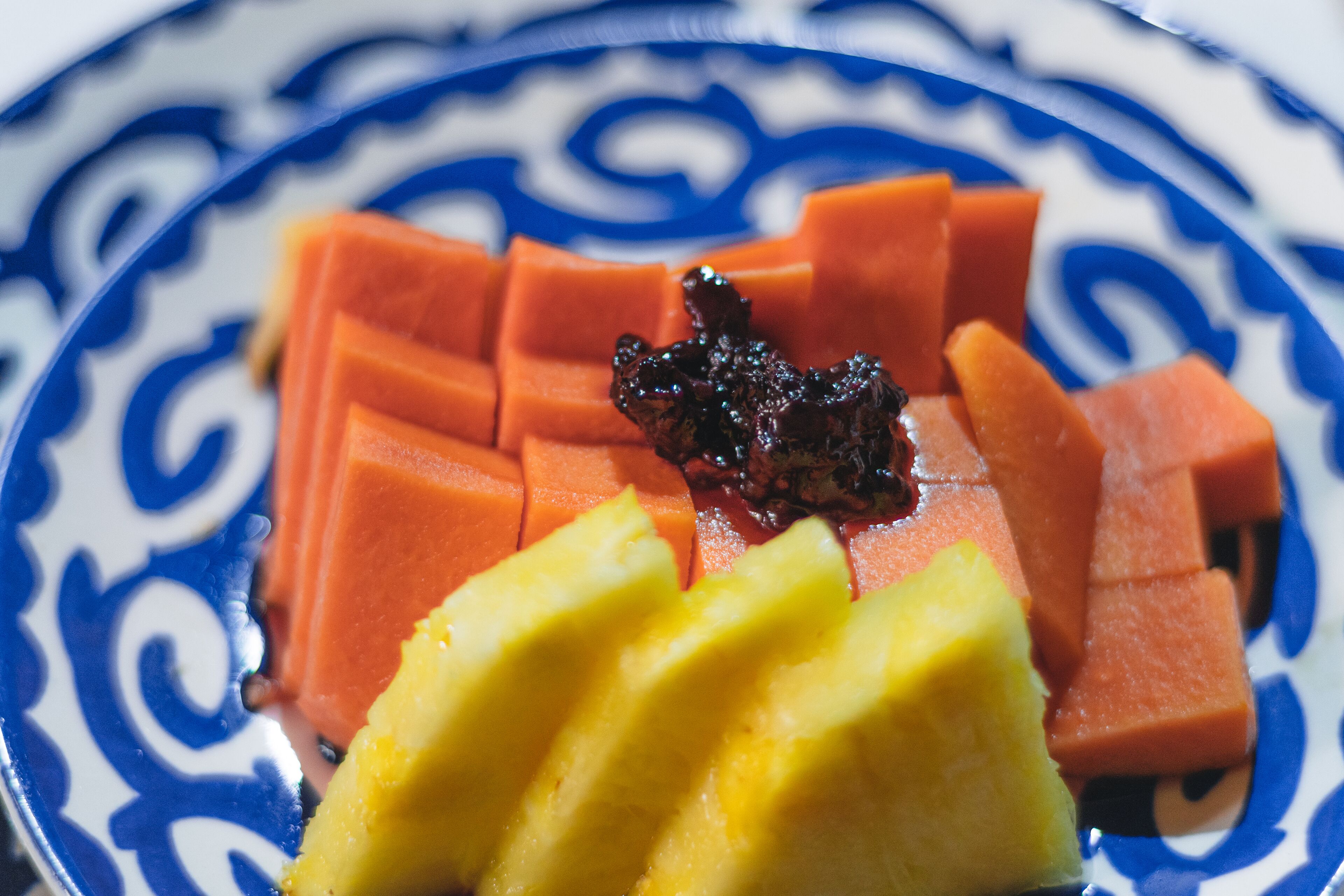 A plate with sliced mango and carrot arranged on a blue and white patterned plate.
