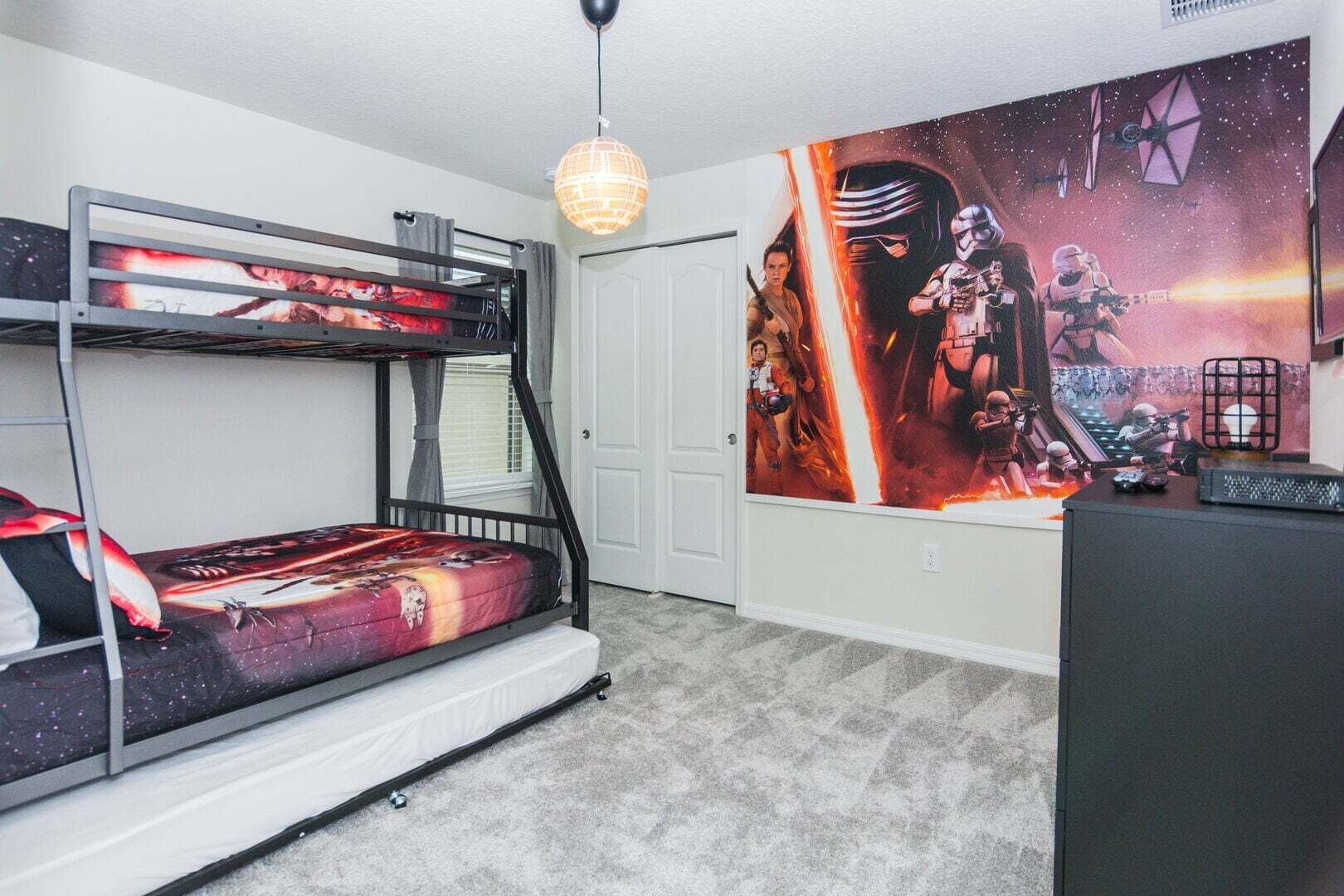A bunk bed with a Star Wars-themed mattress, a Star Wars poster on the wall, and a desk with a computer.