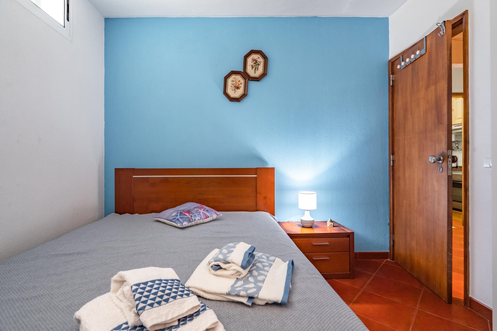 A bedroom with a bed, bedside table, lamp, and a wardrobe.