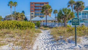Un sendero en la playa que lleva a un edificio con techo azul y un cartel que indica propiedad privada, prohibido el acceso.