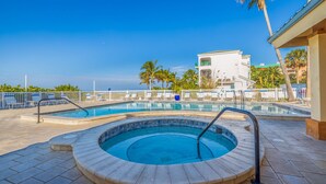 Una piscina con jacuzzi, sillas de descanso y palmeras.