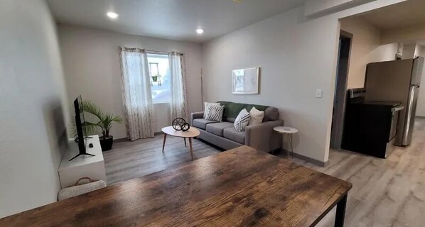 A modern living room with a wooden dining table, a grey sofa, and a small side table. - Elk Loft in Downtown Custer, Sleeps 8, 2 full bath (Custer)