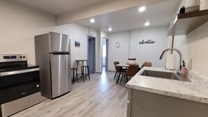 A modern kitchen with stainless steel appliances, a marble countertop, and a dining area with a table and chairs. - Elk Loft in Downtown Custer, Sleeps 8, 2 full bath (Custer)