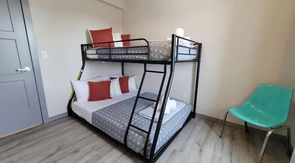 A bunk bed room with a teal chair, a door, and a light switch on the wall. - Elk Loft in Downtown Custer, Sleeps 8, 2 full bath (Custer)
