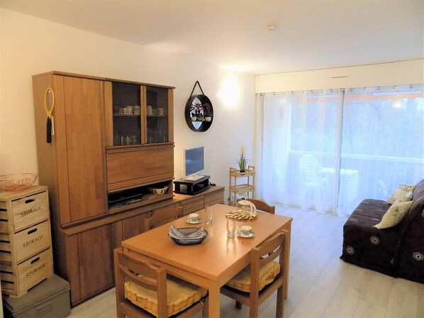 A compact living space with a wooden dining table, a sofa, and a built-in wooden cabinet with glass doors.