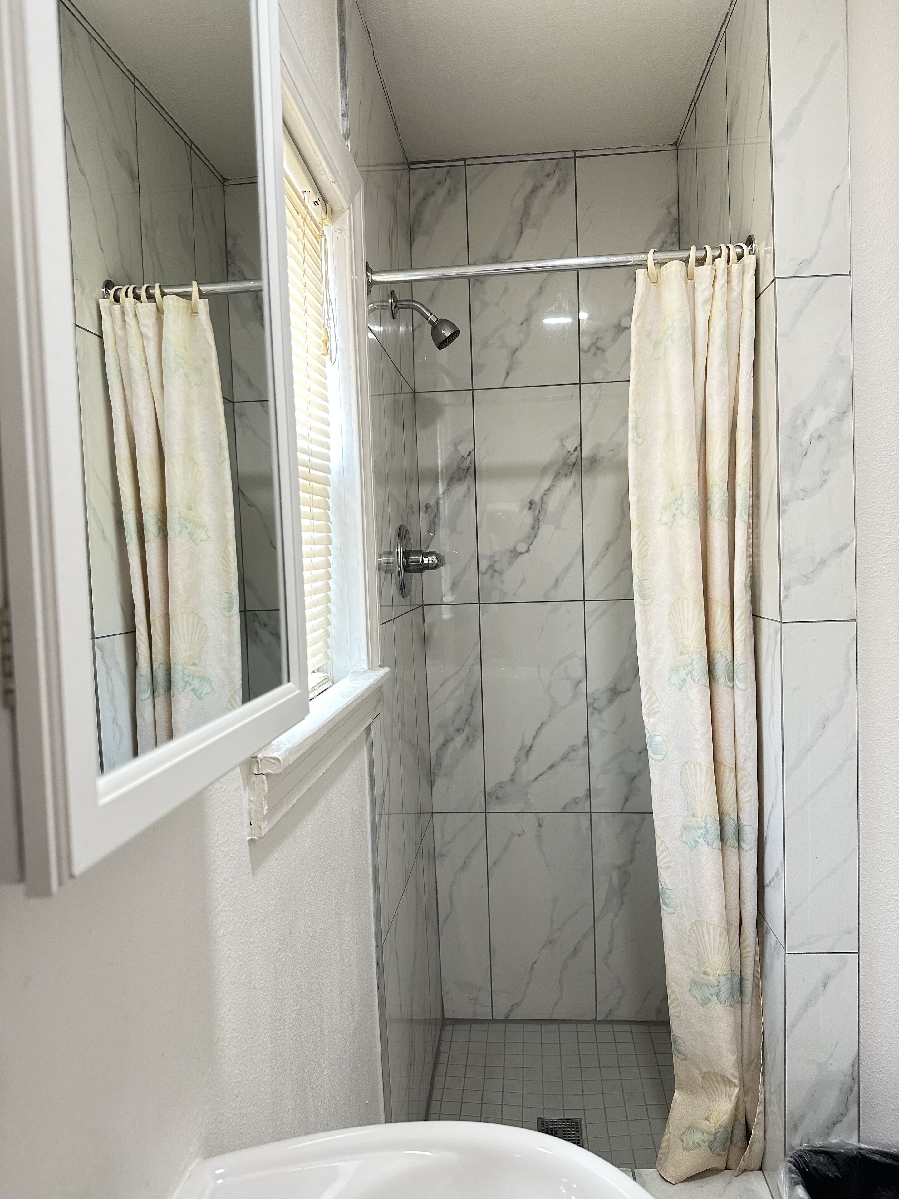 Un baño con ducha, ventana y espejo.