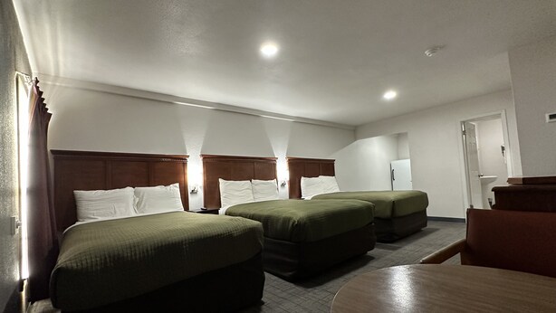 Una habitación de hotel con dos camas individuales, un cabecero de madera, una mesita redonda pequeña y una silla.