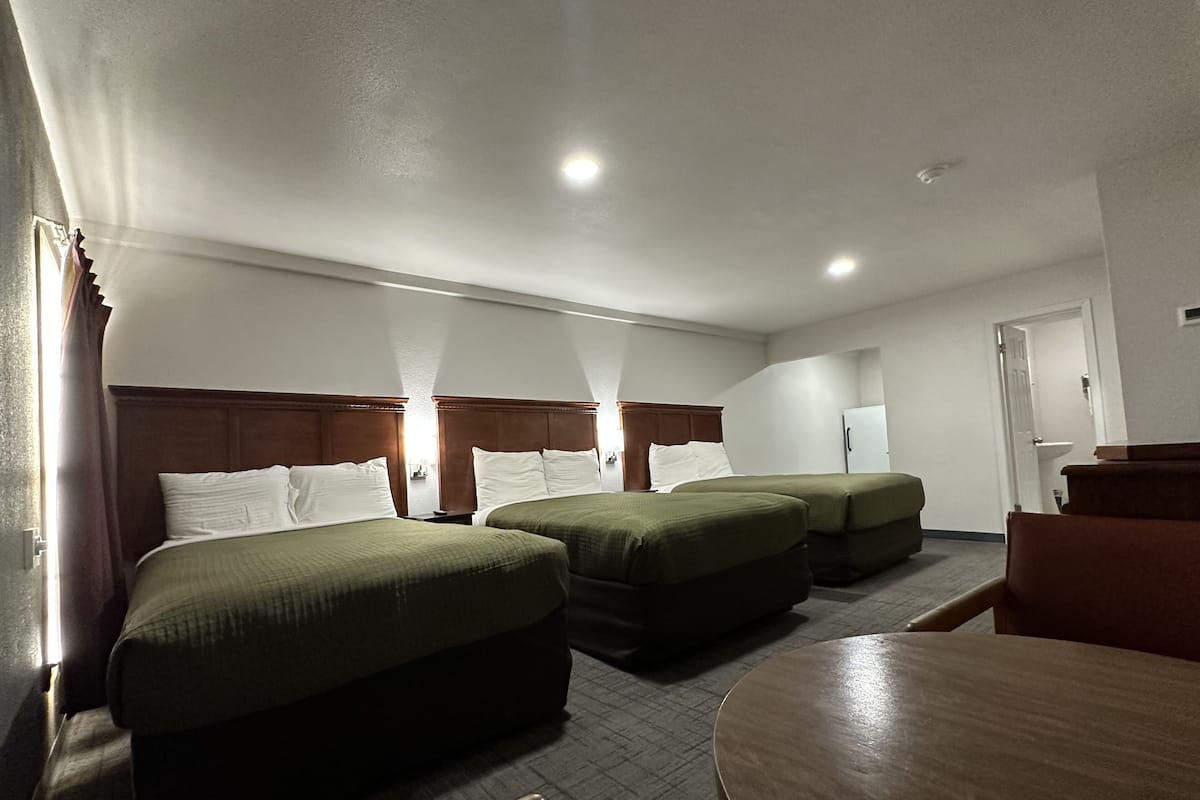 A hotel room with two single beds, a wooden headboard, a small round table, and a chair.