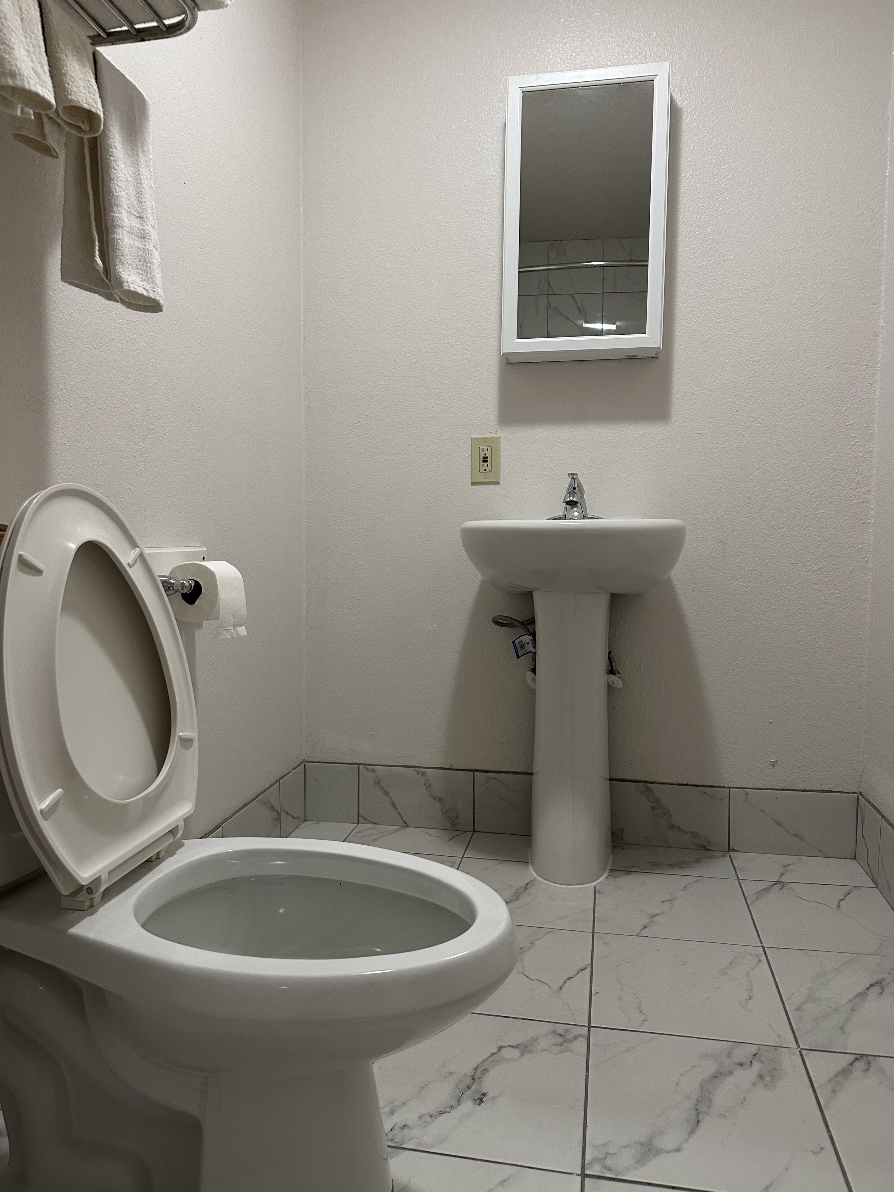Un baño con inodoro, lavamanos y espejo.