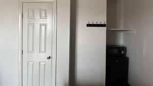 Una puerta blanca con una cerradura y un pequeño estante con ganchos encima.