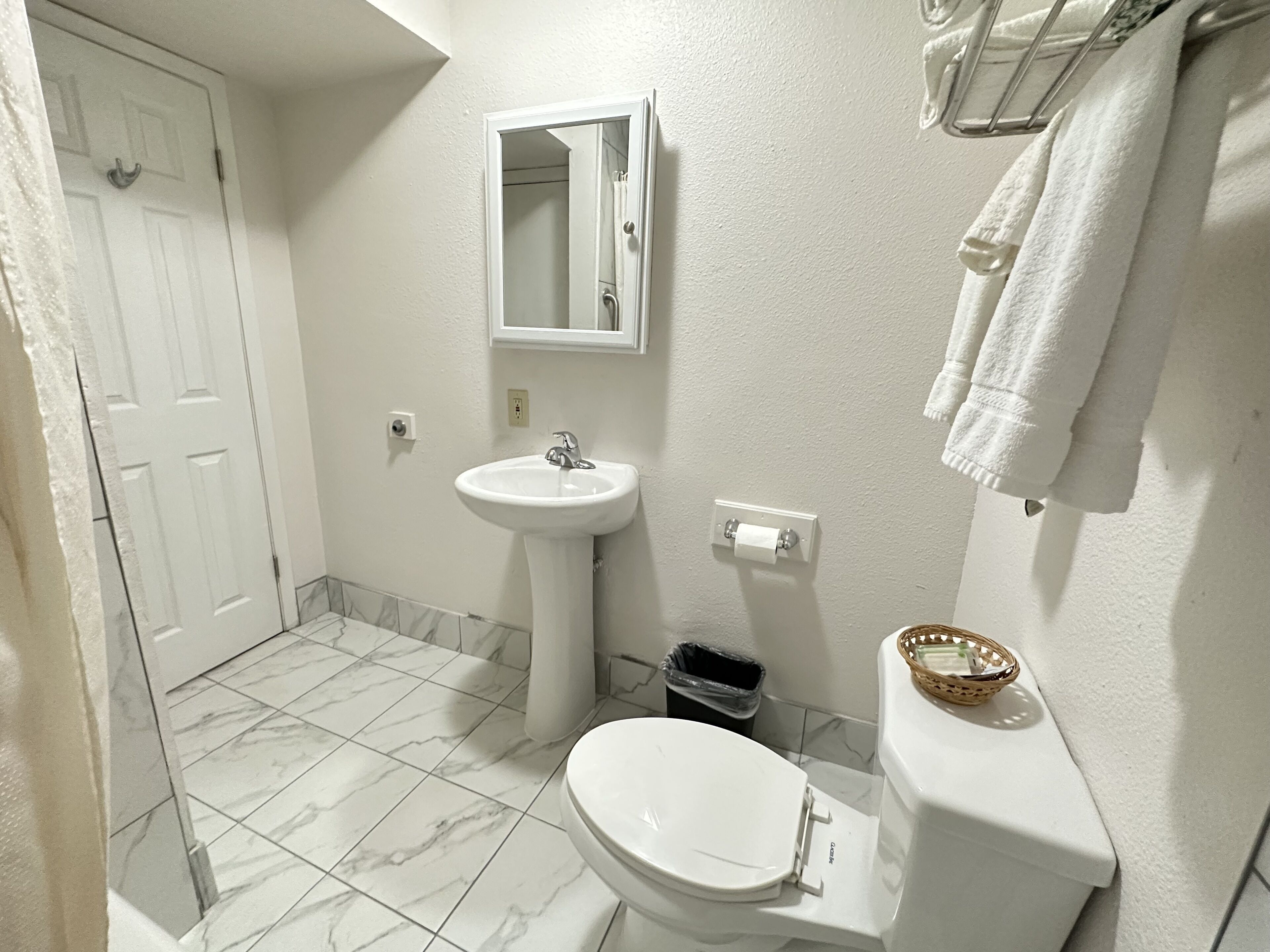 A bathroom with a toilet, sink, and mirror.